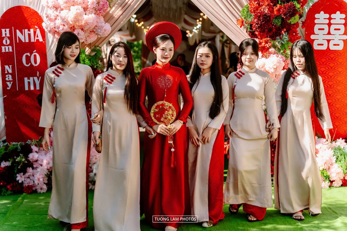 Cô dâu áo dài đỏ cùng các phù dâu áo dài trắng trước cổng hoa nhà gái