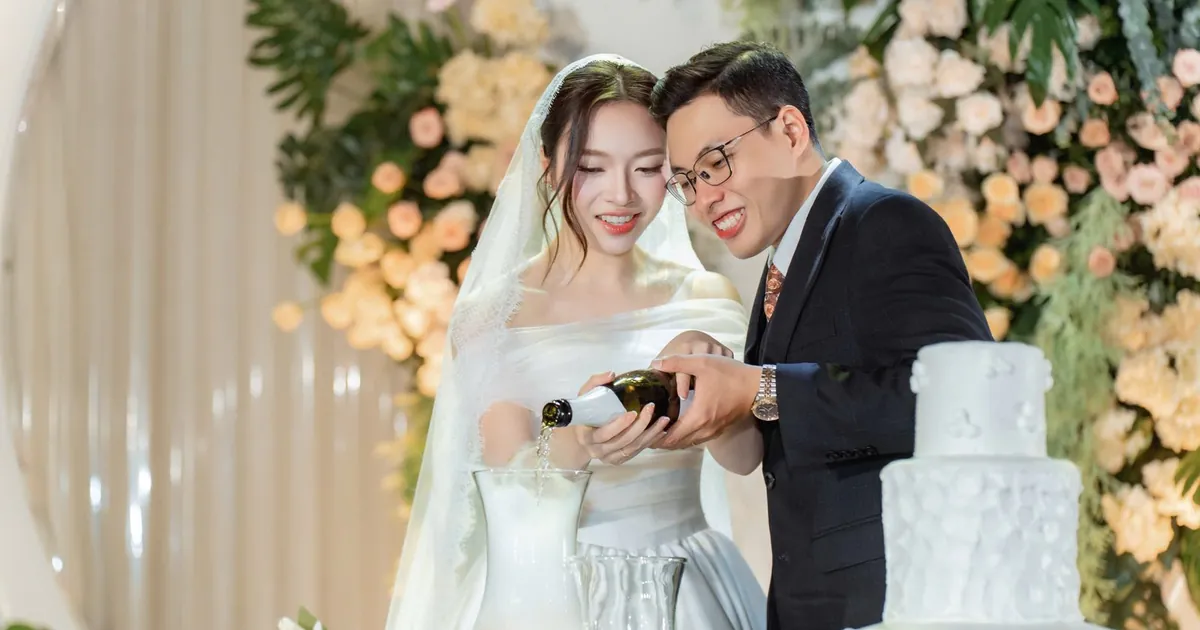 Cô dâu chú rể rót rượu mừng bên bánh cưới trong tiệc cưới